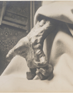 Main crispée (bronze) surgissant des plis d'une couverture