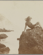 Femme non identifiée posant sur un rocher devant la mer